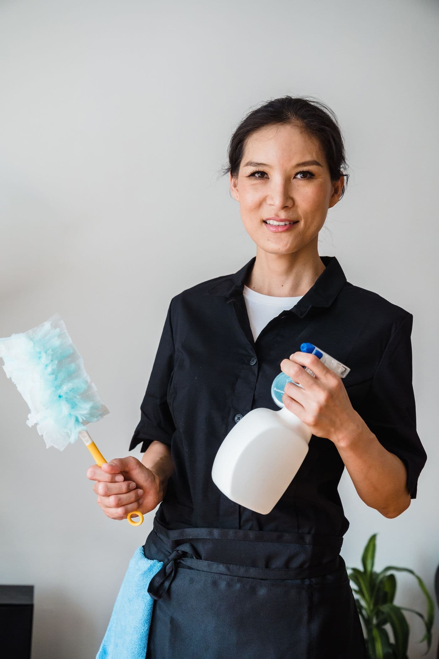 Intervenante SLN Multiservices en tenue, plumeau et vaporisateur à la main
